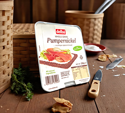 Packaged delba Pumpernickel bread on a wooden surface with a knife and herbs.